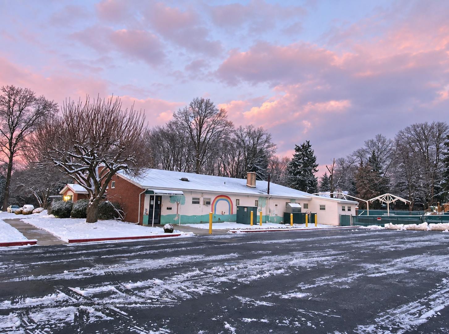 Snow-covered building with a rainbow mural during a sunset