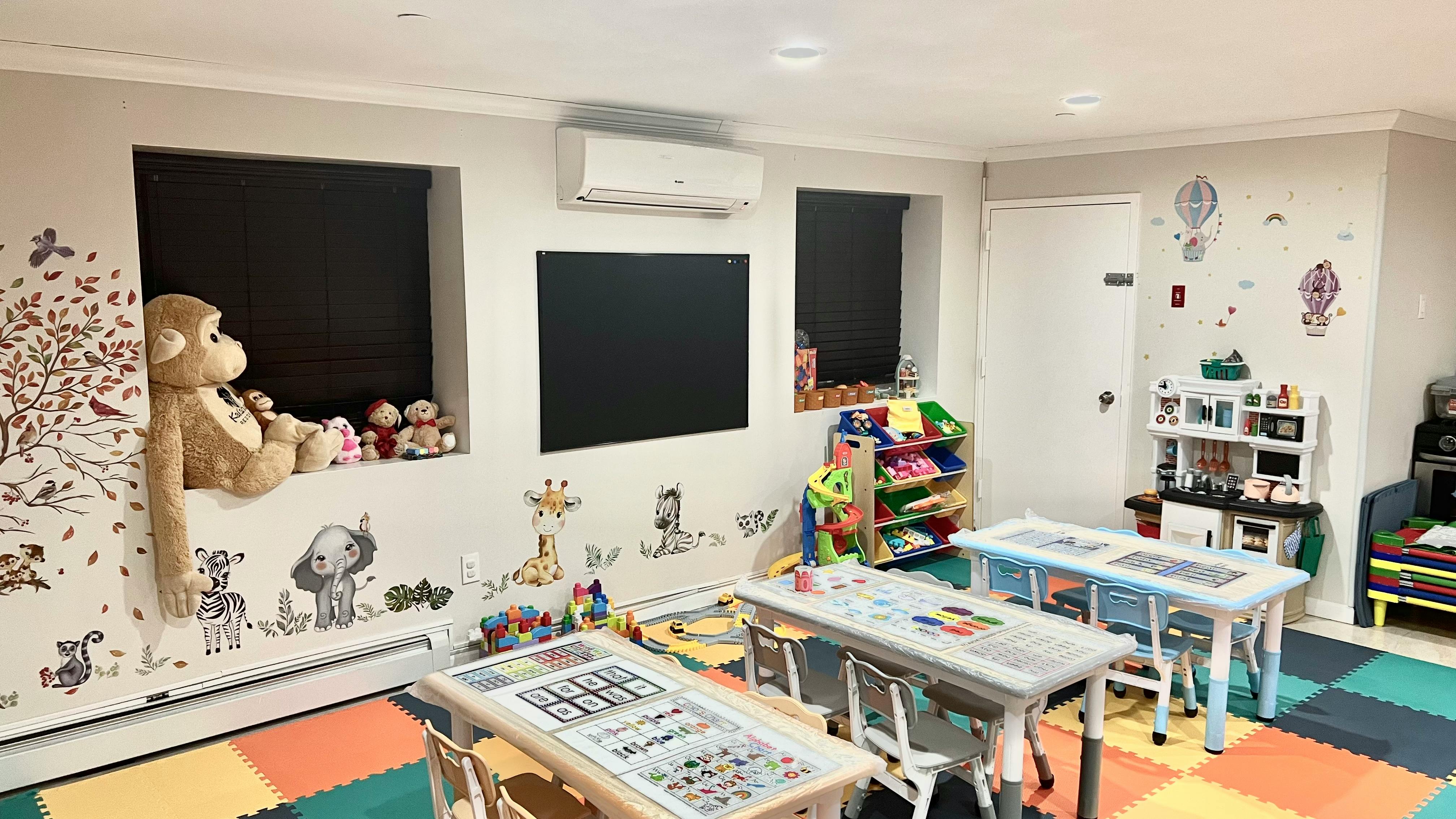 Playroom with small tables and chairs, toys, and wall decals