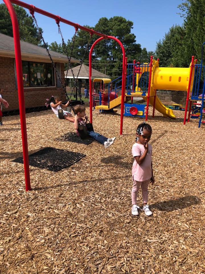 Children playing on a playground with swings and a slide