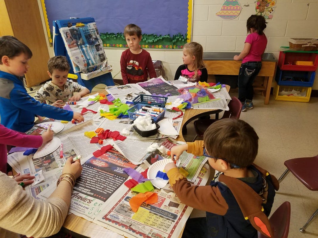 Children doing crafts at a table in a classroom