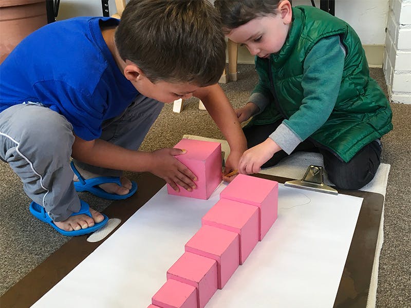 Two children building with pink blocks