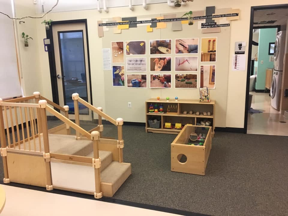 Indoor play area with wooden steps and railing, shelves, and wall art