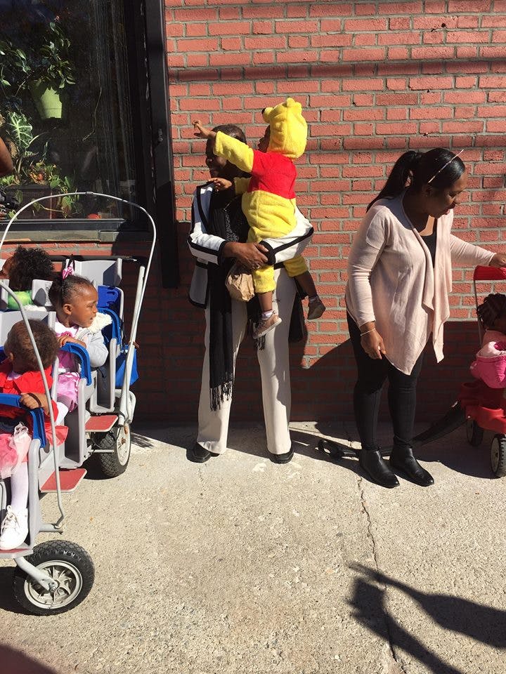 Person holding a child in a Winnie the Pooh costume pointing
