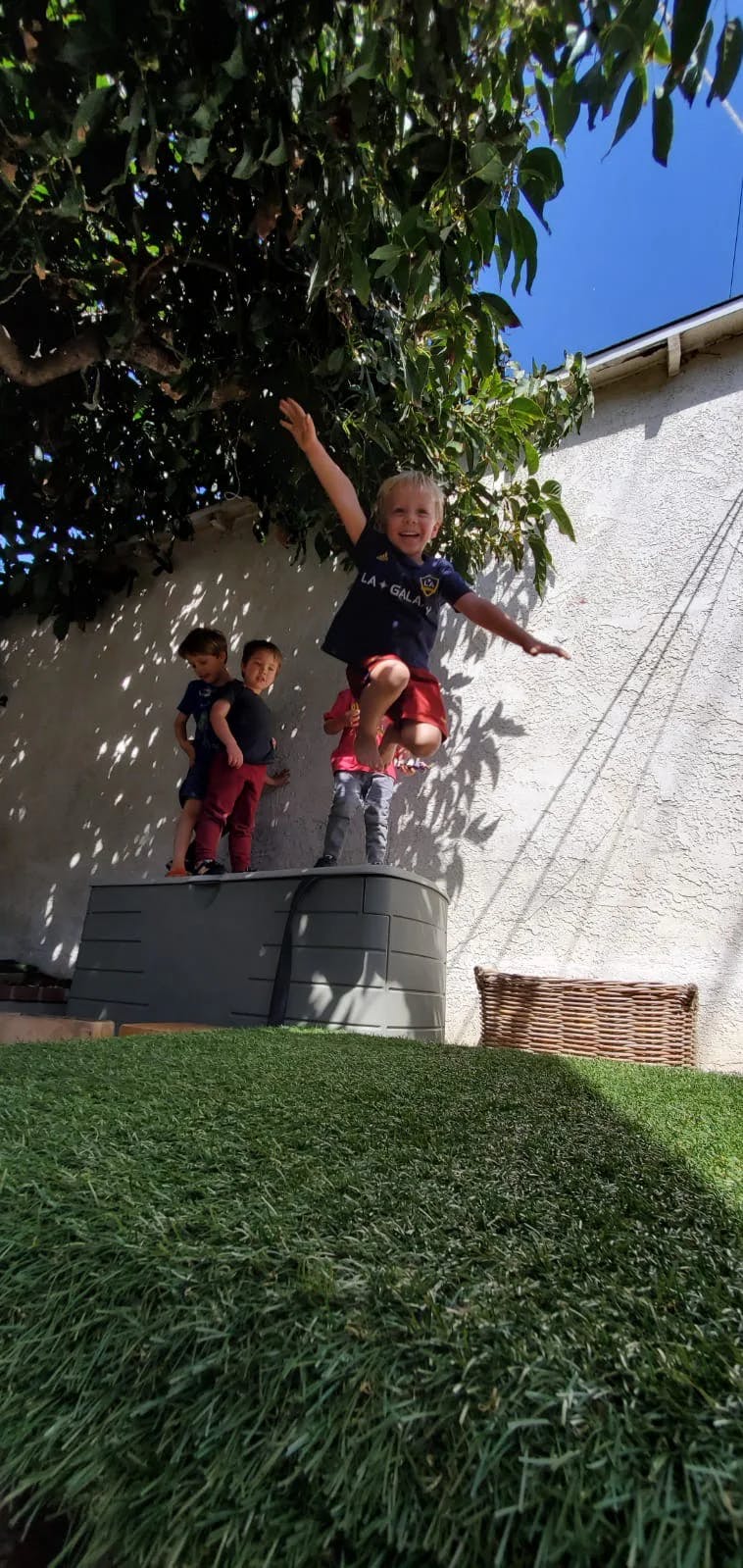 Three children playing outdoors, one child jumping in the air