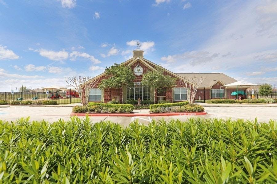 Brick building with a clock on the facade and green landscaping