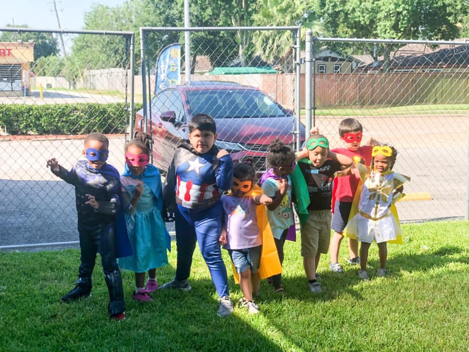 Group of children in superhero costumes standing on grass