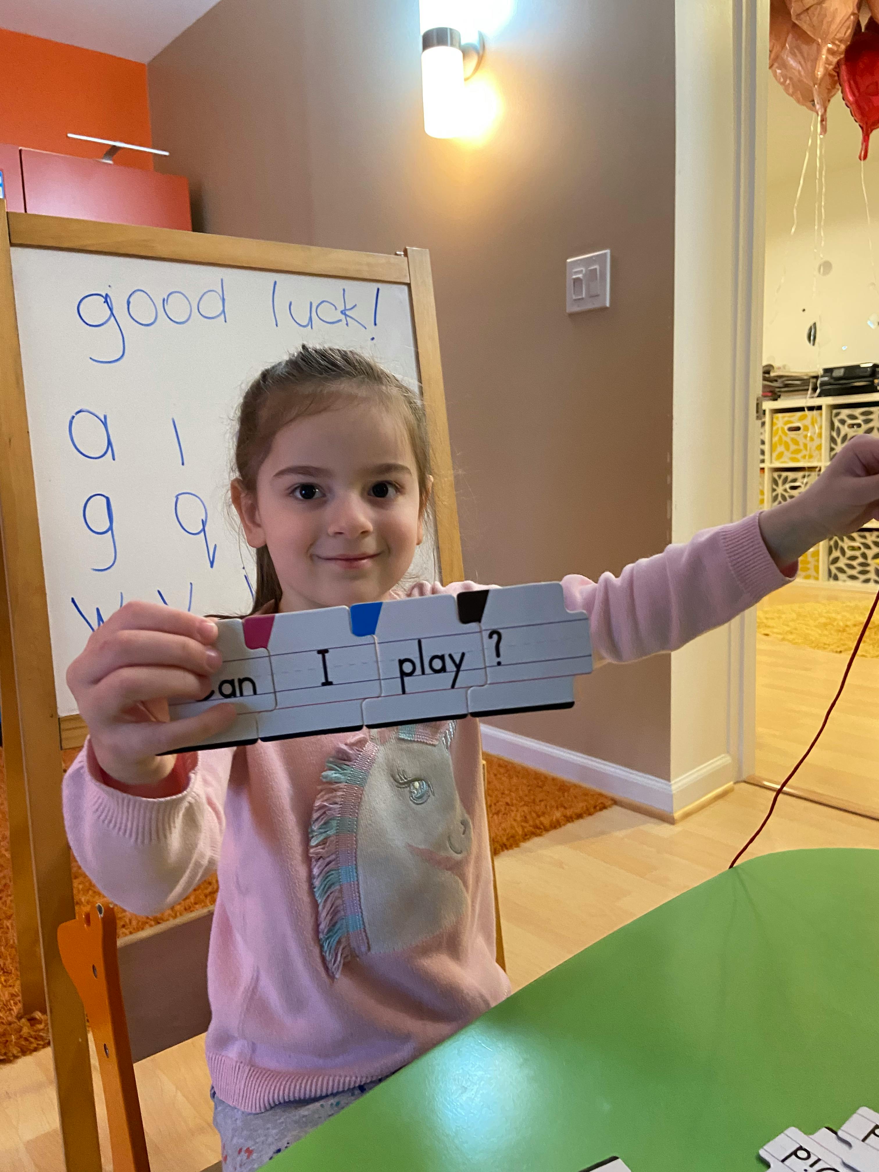 Child holding up a sign that reads "Can I play?"