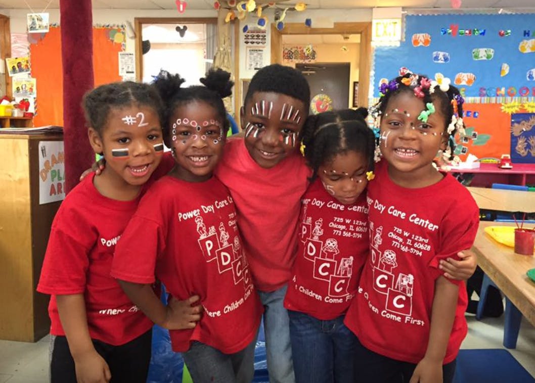 Five children in red shirts with face paint in a classroom