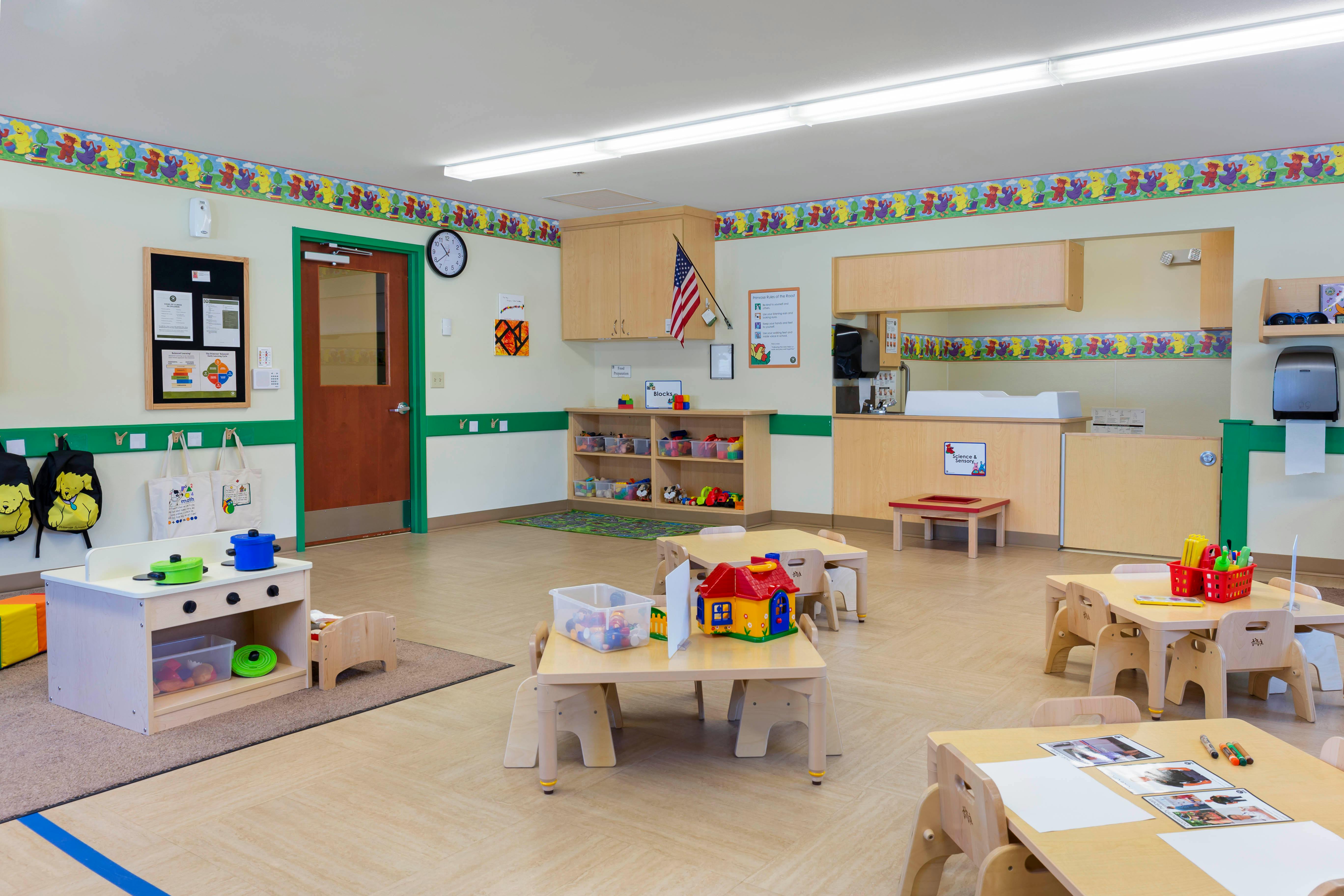 Classroom with play kitchen, small tables with chairs, and toys