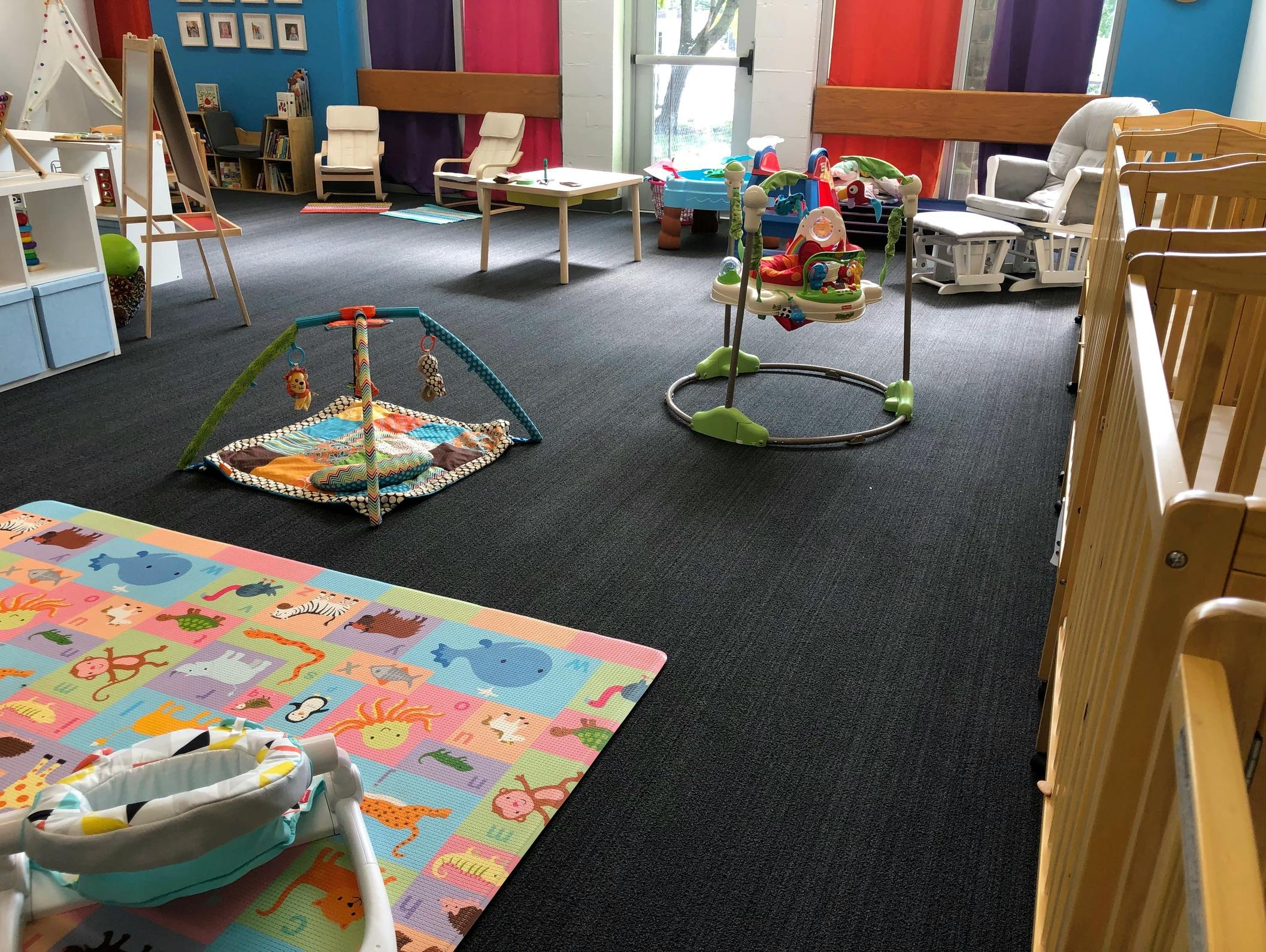 Playroom with colorful mat, baby activity gym, and bouncer