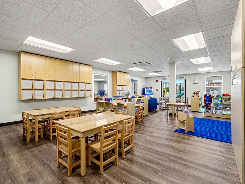 Empty classroom with small tables and chairs, and storage
