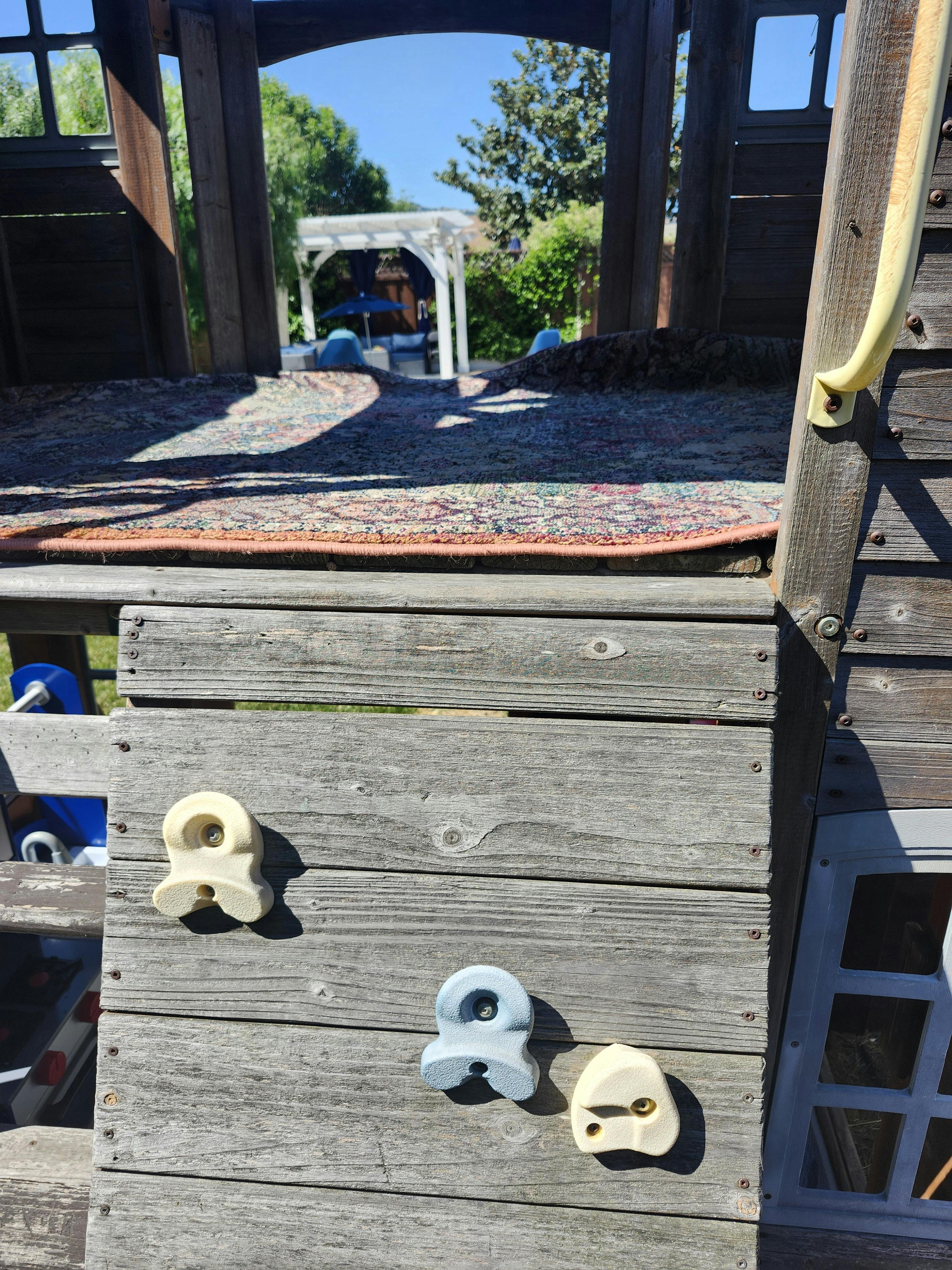 Wooden playground structure with climbing holds
