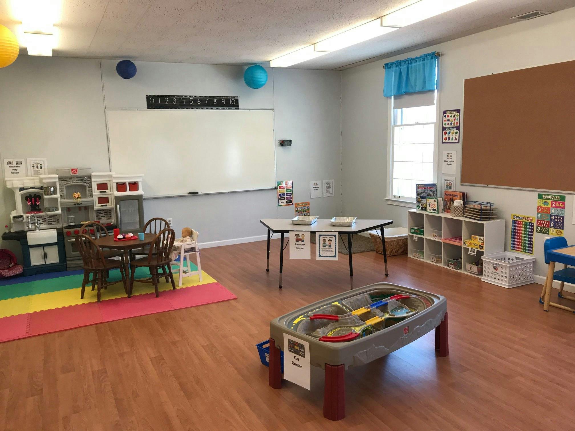 Empty classroom with small tables, chairs, and a whiteboard