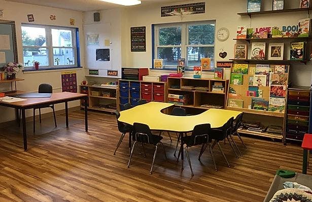 Classroom with small tables and chairs, bookshelves, and windows