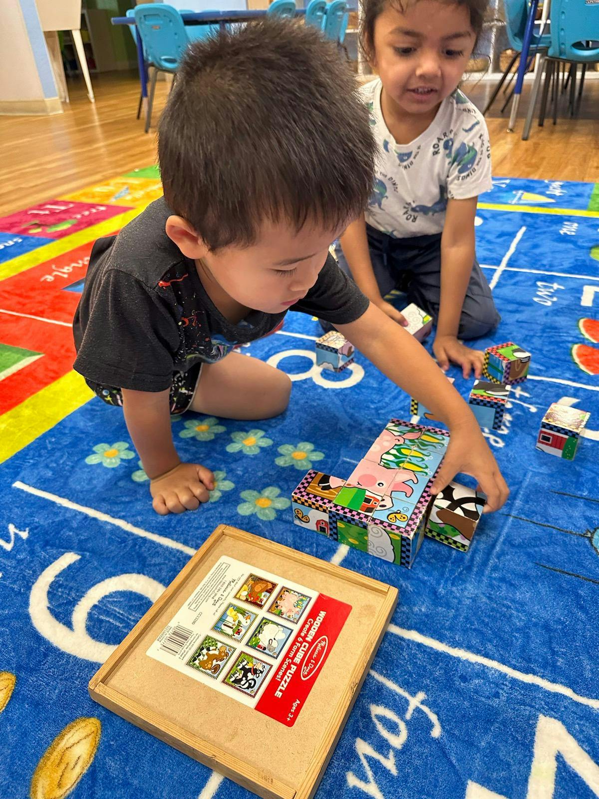 Two children playing with blocks on a blue mat