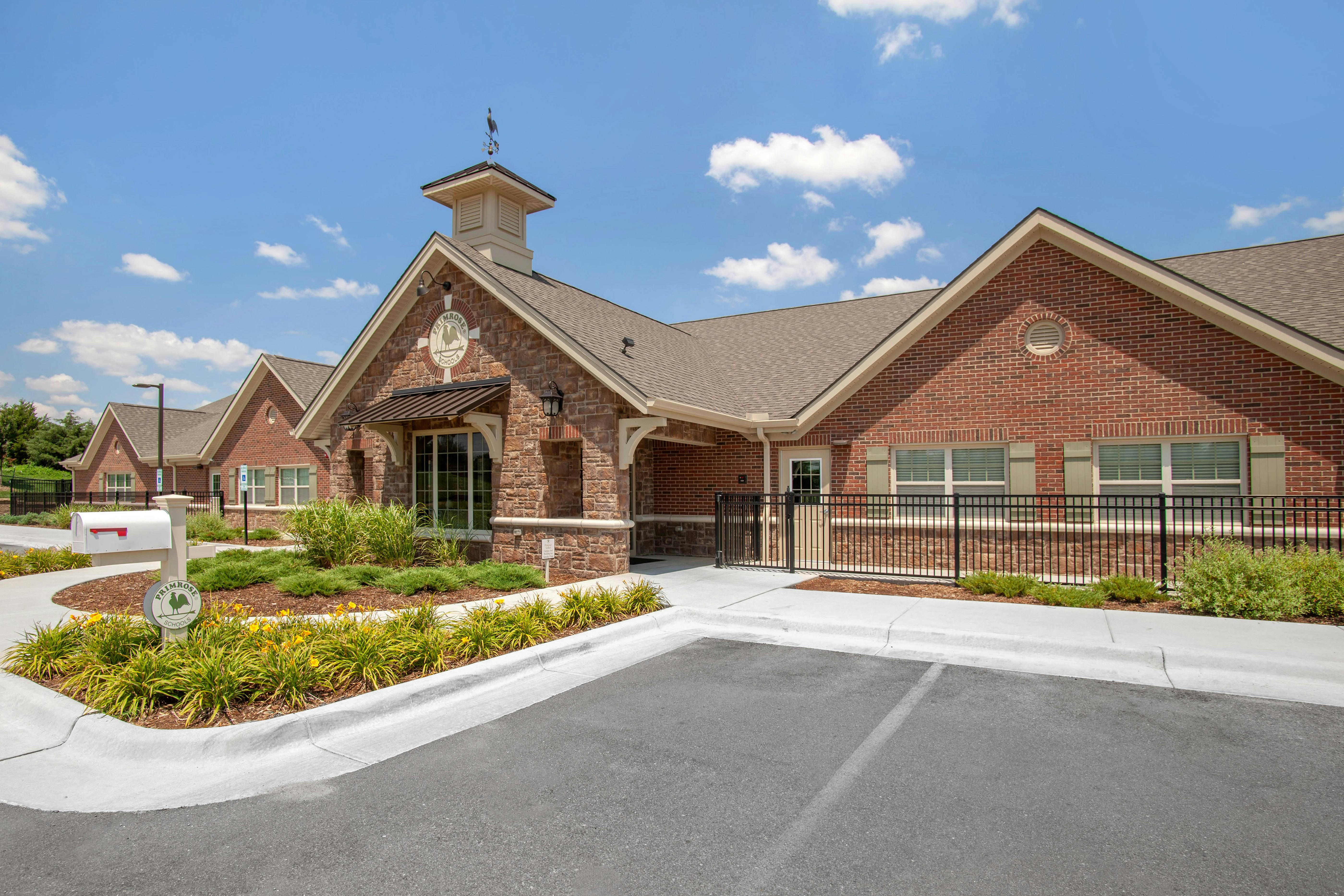 Brick building with stone accents, a cupola, and a Primrose Schools sign
