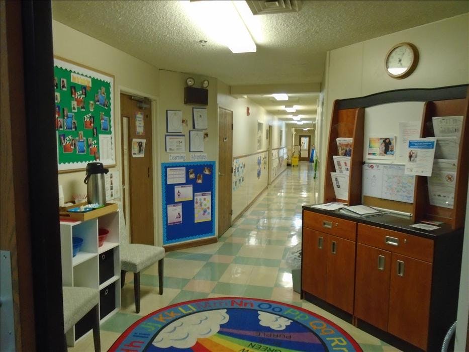 A long hallway with bulletin boards and furniture on the sides