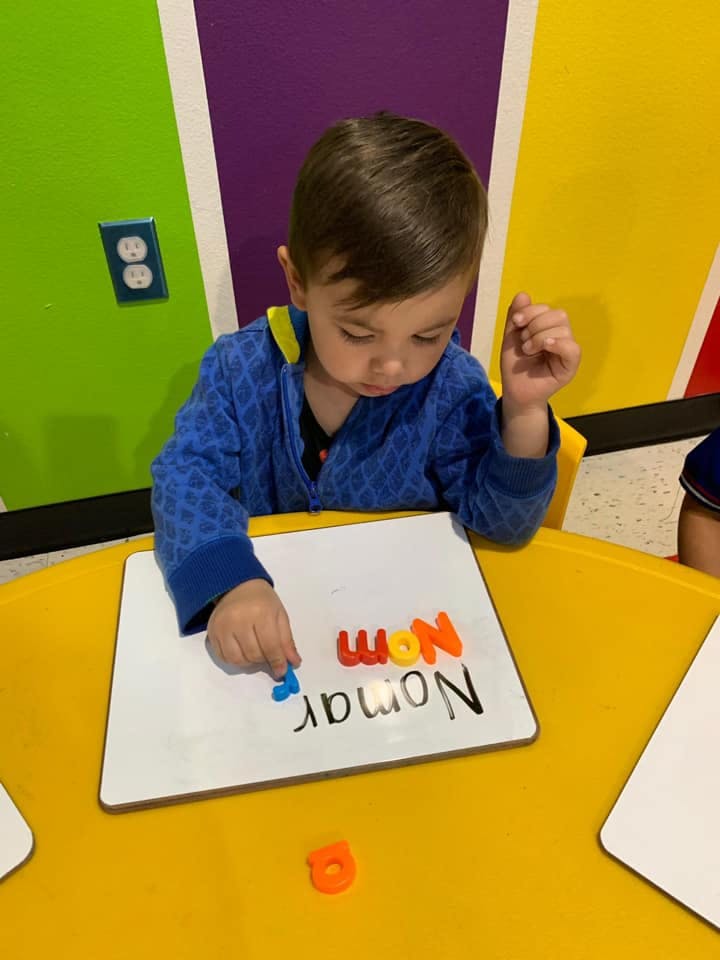 Child playing with letter magnets on a whiteboard