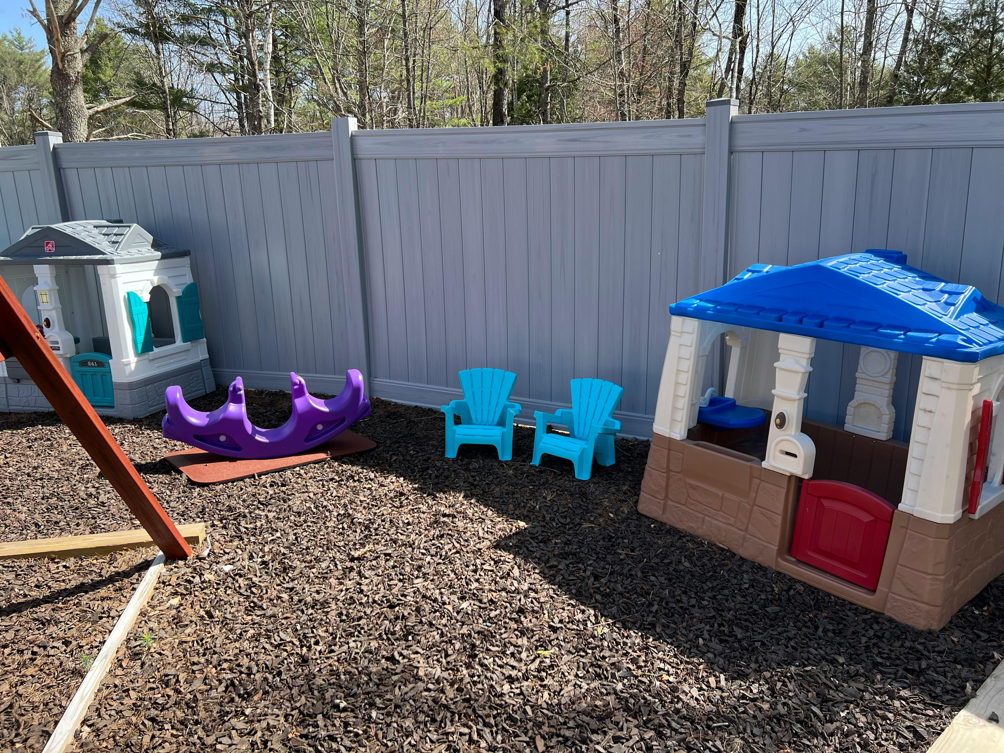 Playhouses and chairs in a fenced yard