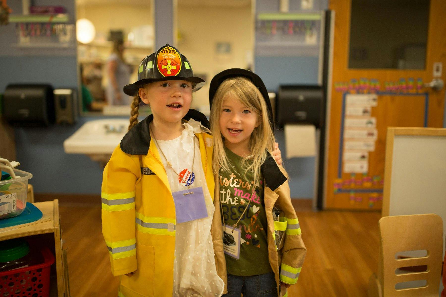 Two children in firefighter costumes standing together