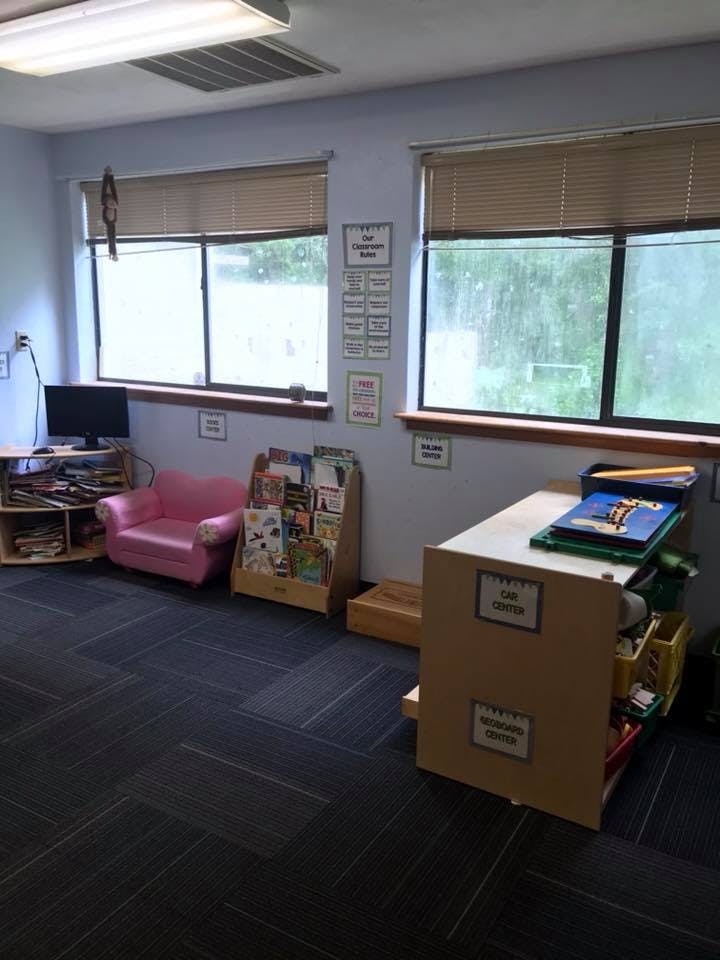 Children's reading area with a pink armchair, book display, and windows