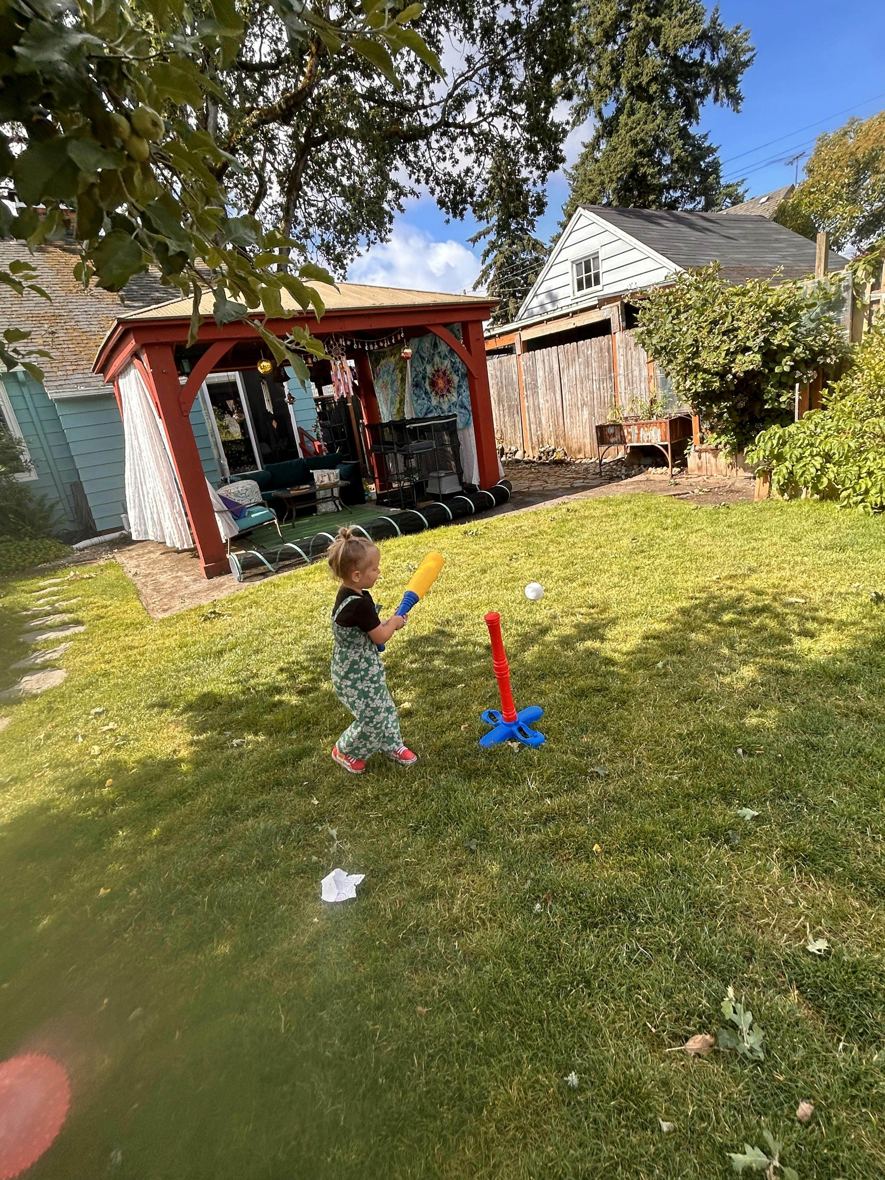 Child playing tee-ball in a backyard