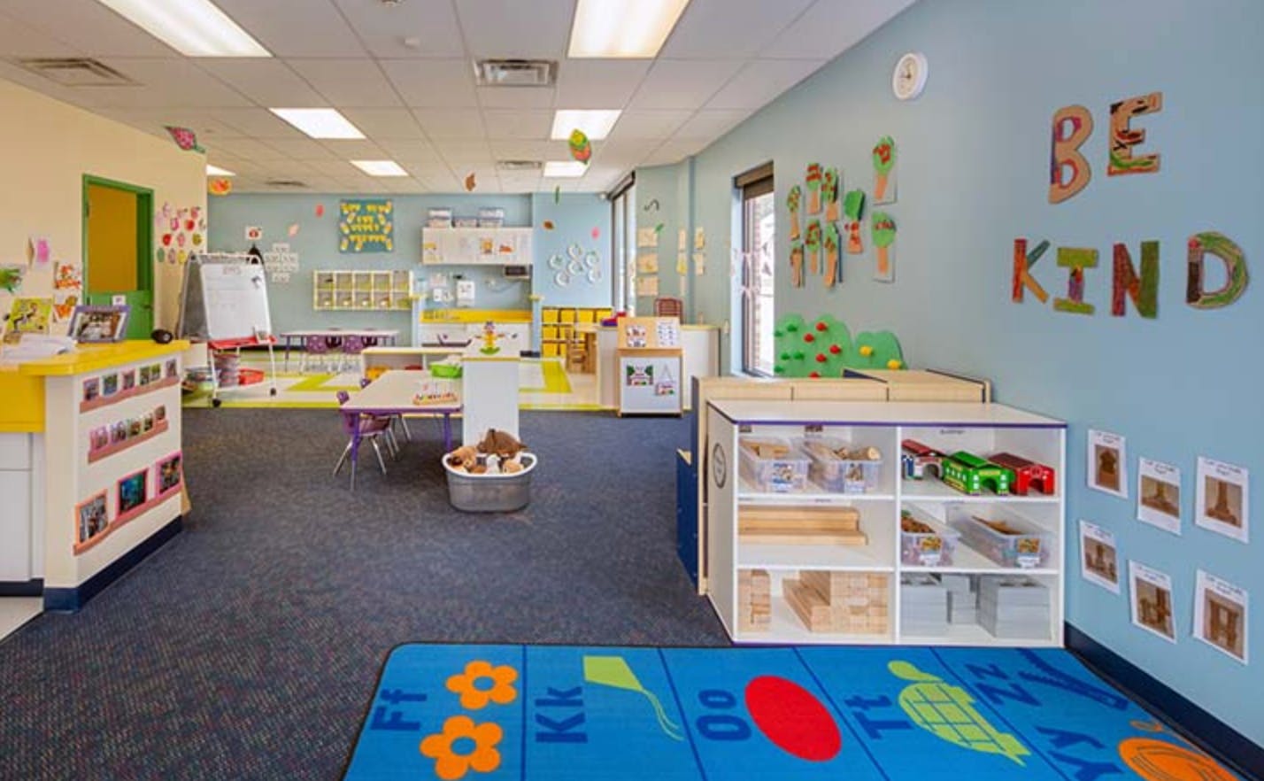 Empty classroom with blue walls and a blue rug with letters and shapes