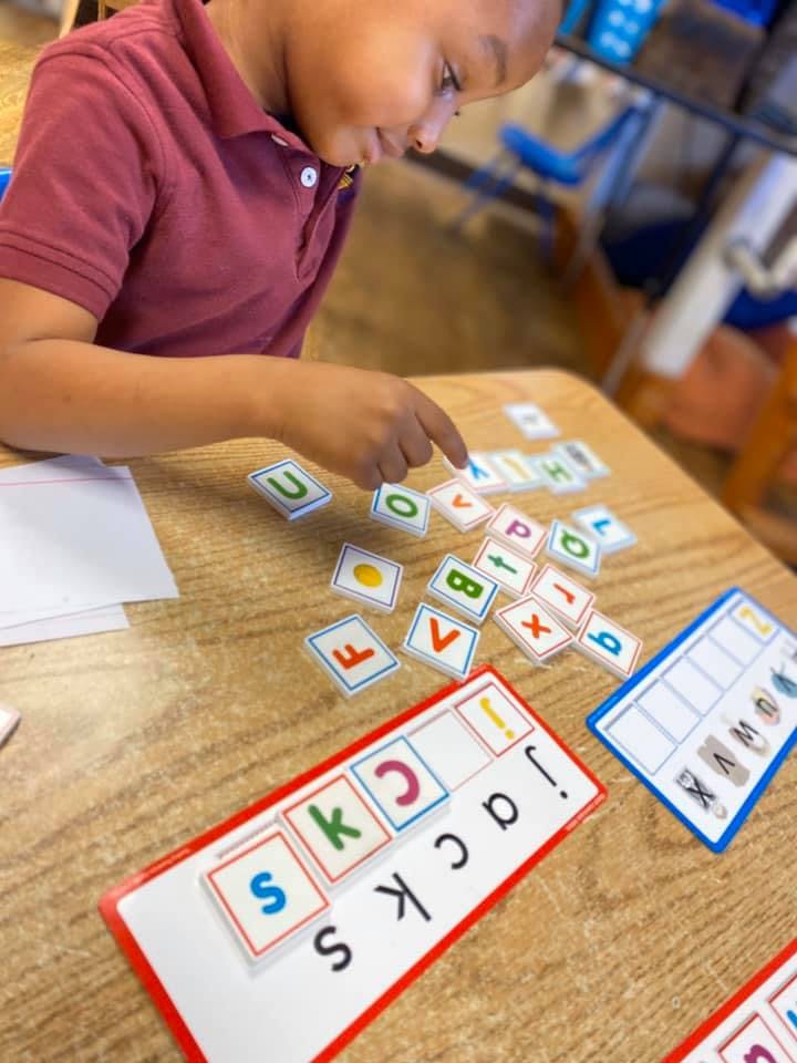 Child playing with letter tiles on a wooden table