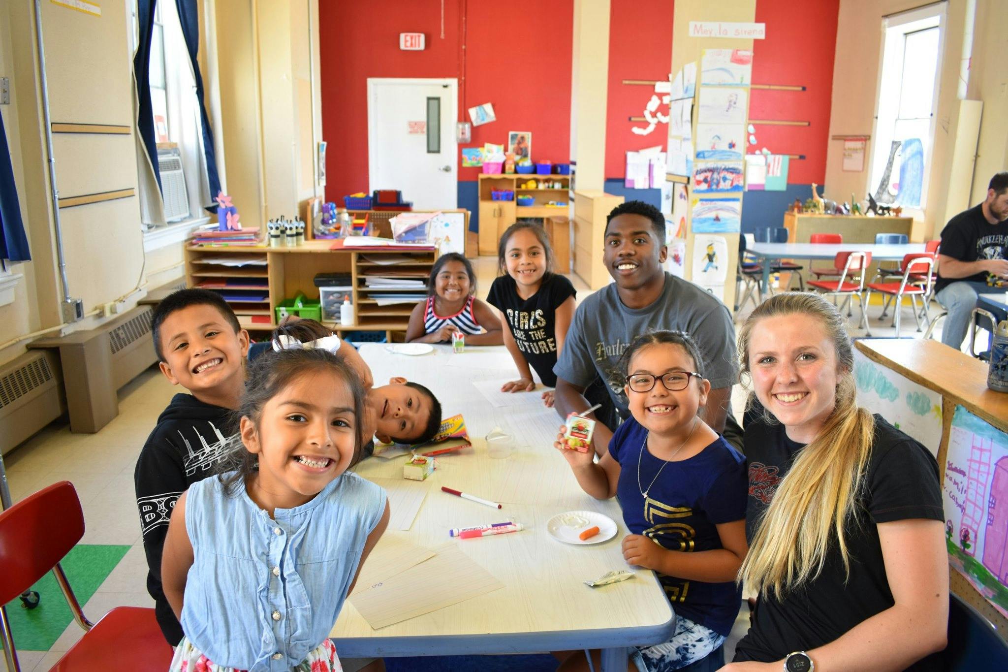 Adults and children smiling around a table in a classroom