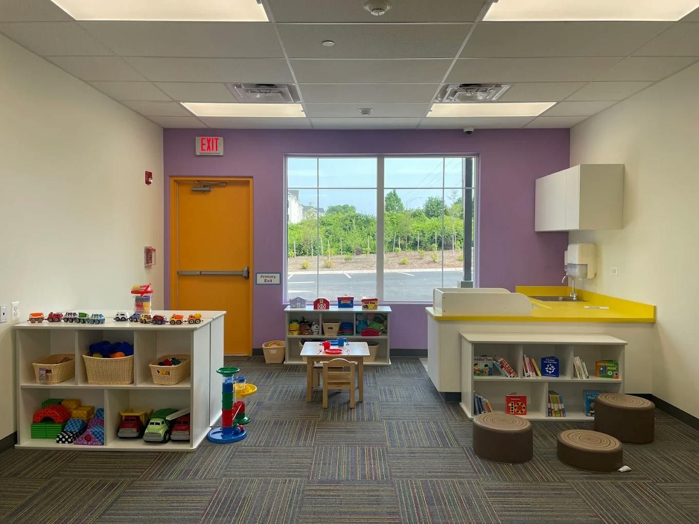 Classroom with small tables, chairs, and shelves filled with toys