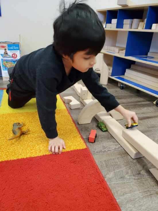 Child playing with toy cars on a wooden ramp