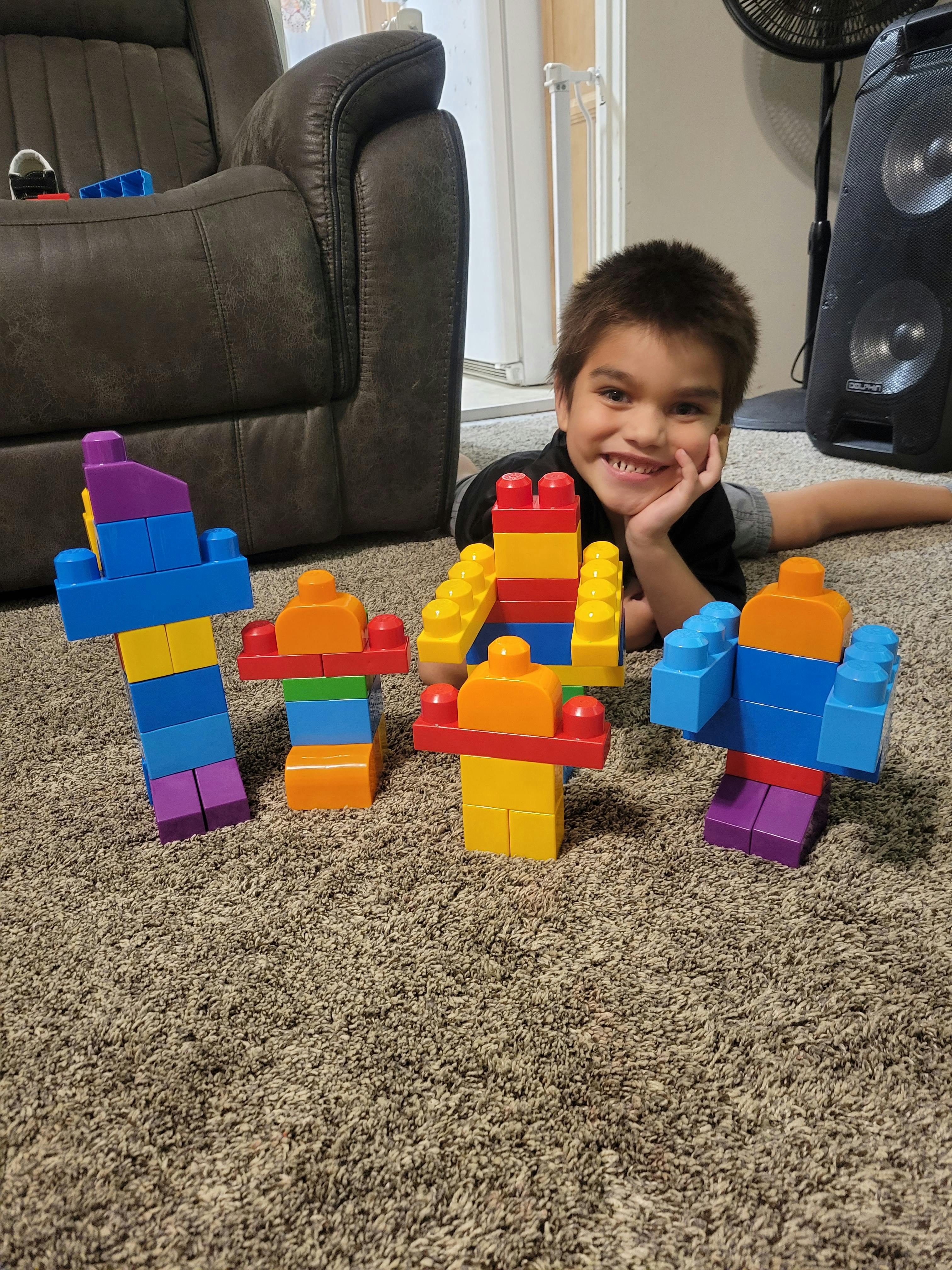 Child lying on carpet with colorful block figures