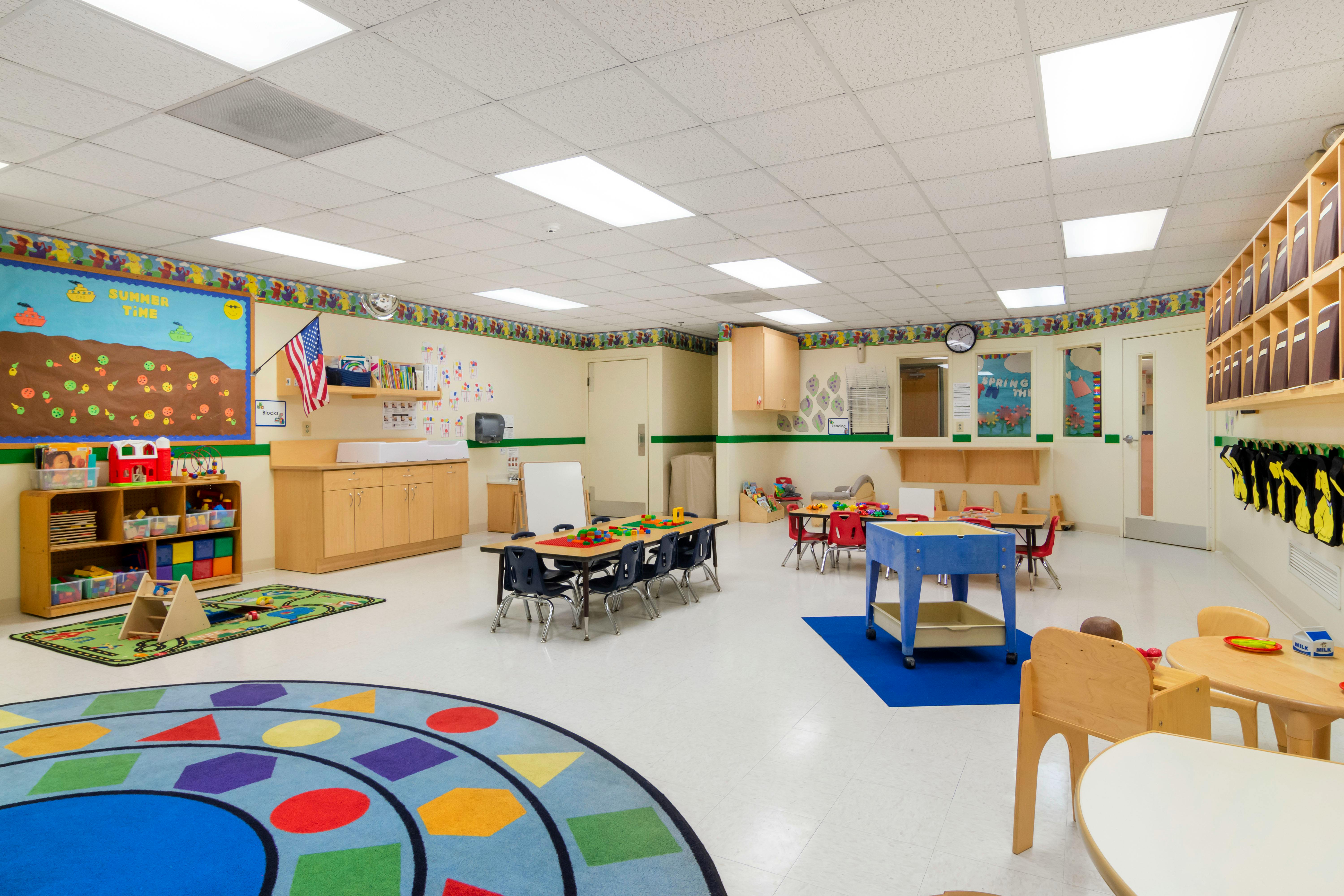 A colorful and tidy classroom with small tables, chairs, and play areas