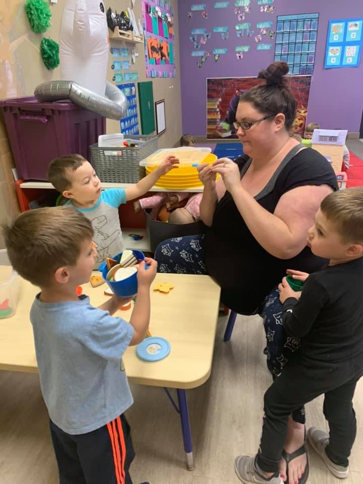 Adult and three children interacting around a table in a classroom