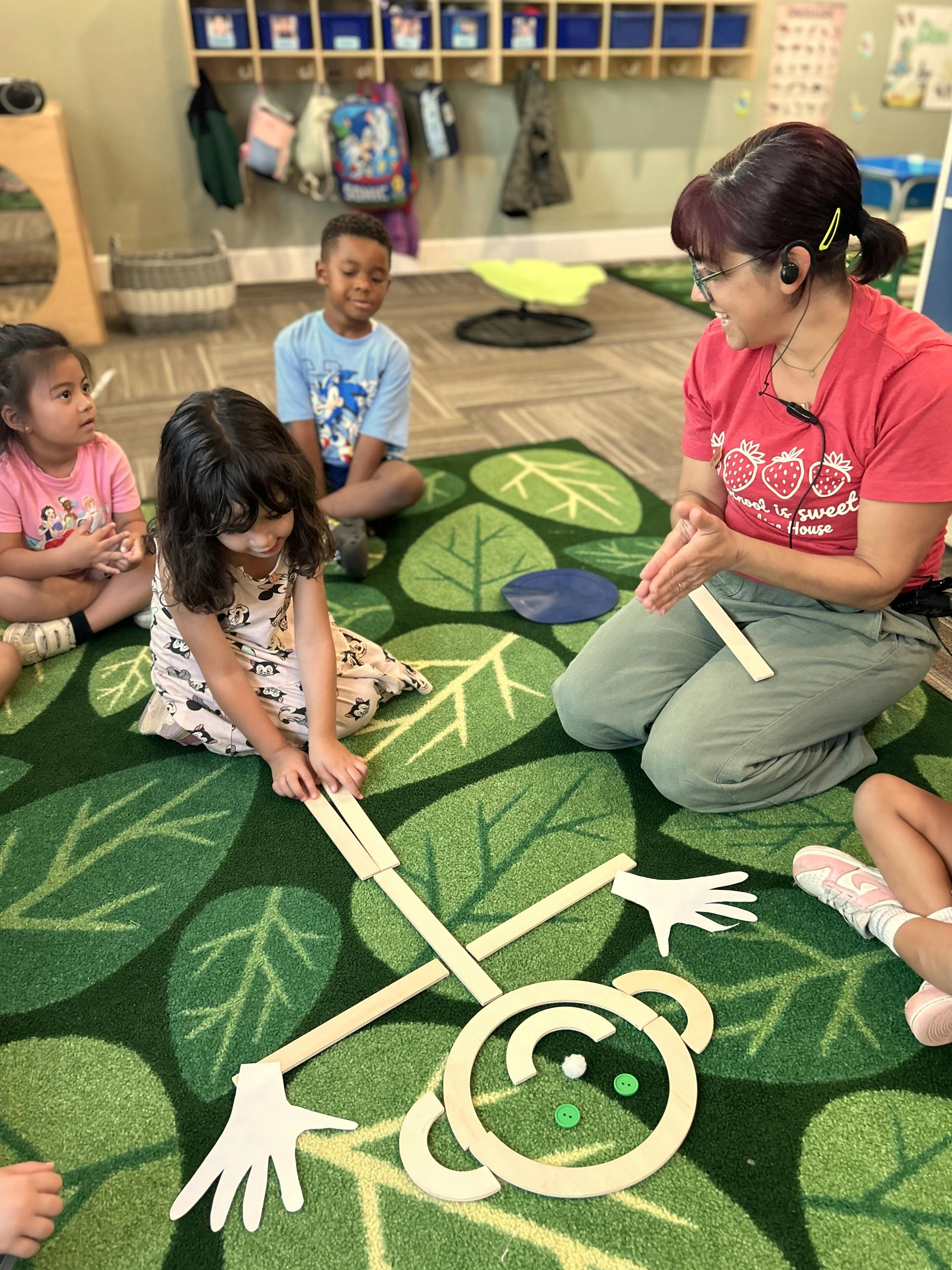 Teacher and children building a wooden figure on a rug in a classroom