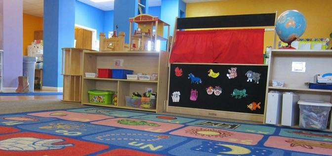 Playroom with alphabet rug, shelves, and puppet theater
