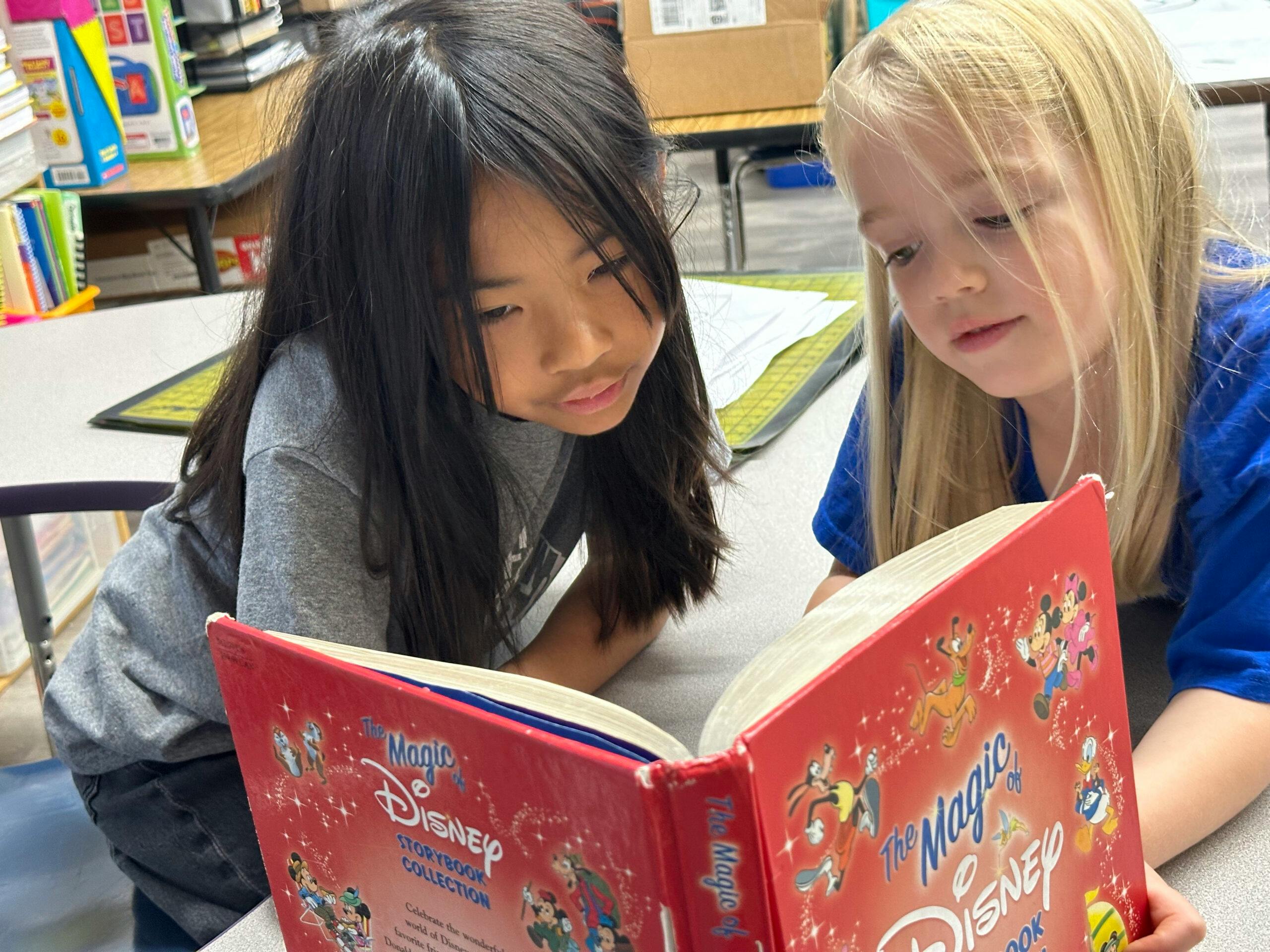 Two children reading a red Disney storybook together