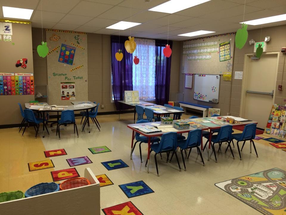 Classroom with tables, chairs, and alphabet squares on the floor