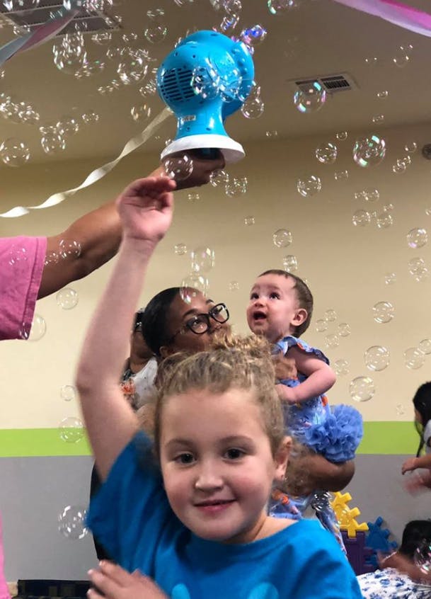 Person holding a bubble machine above children