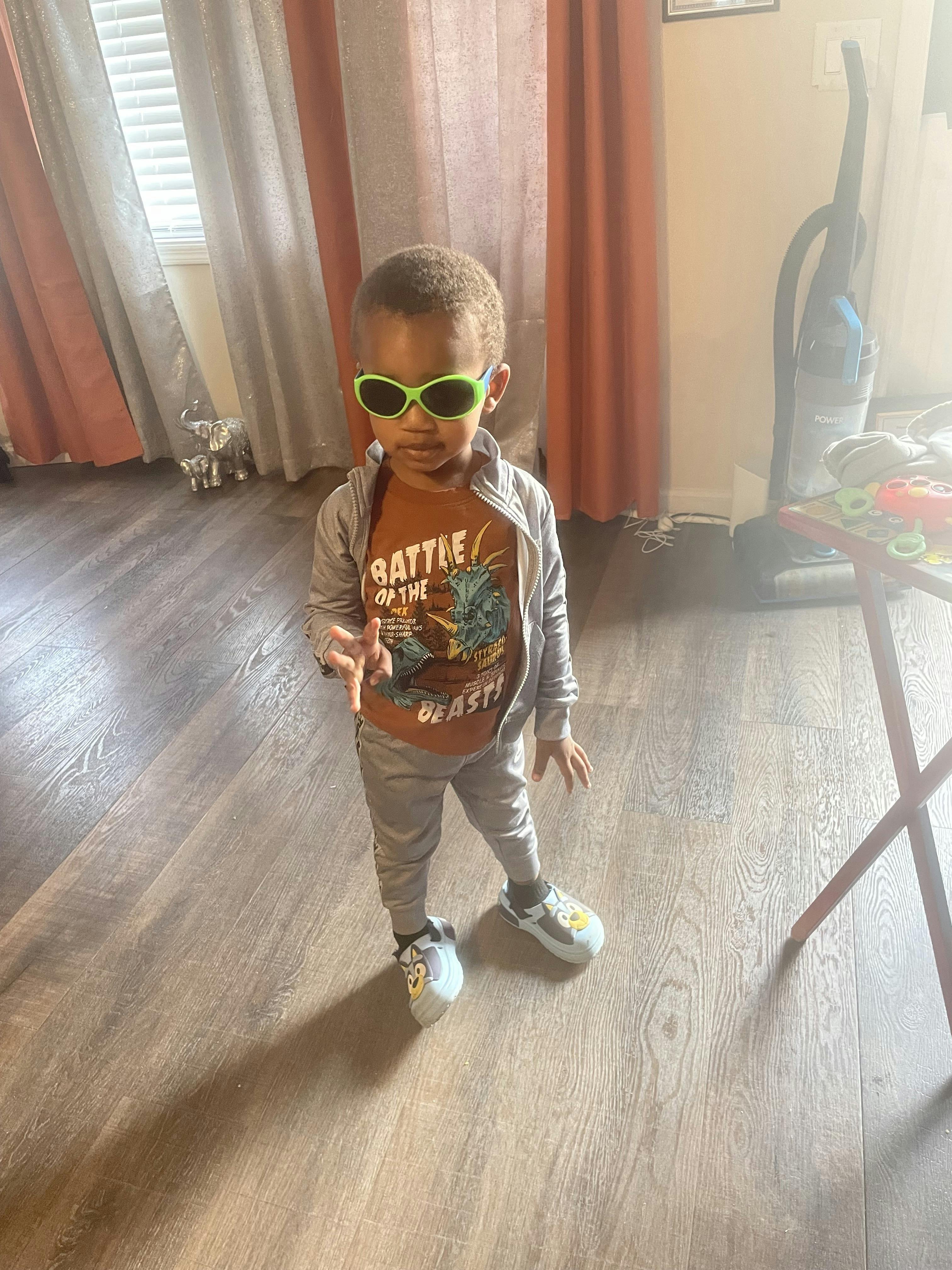 Child wearing sunglasses and a t-shirt with "BATTLE OF THE AST"