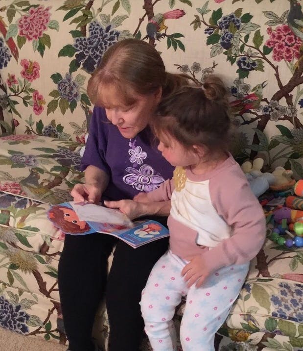 Person and child reading a book together