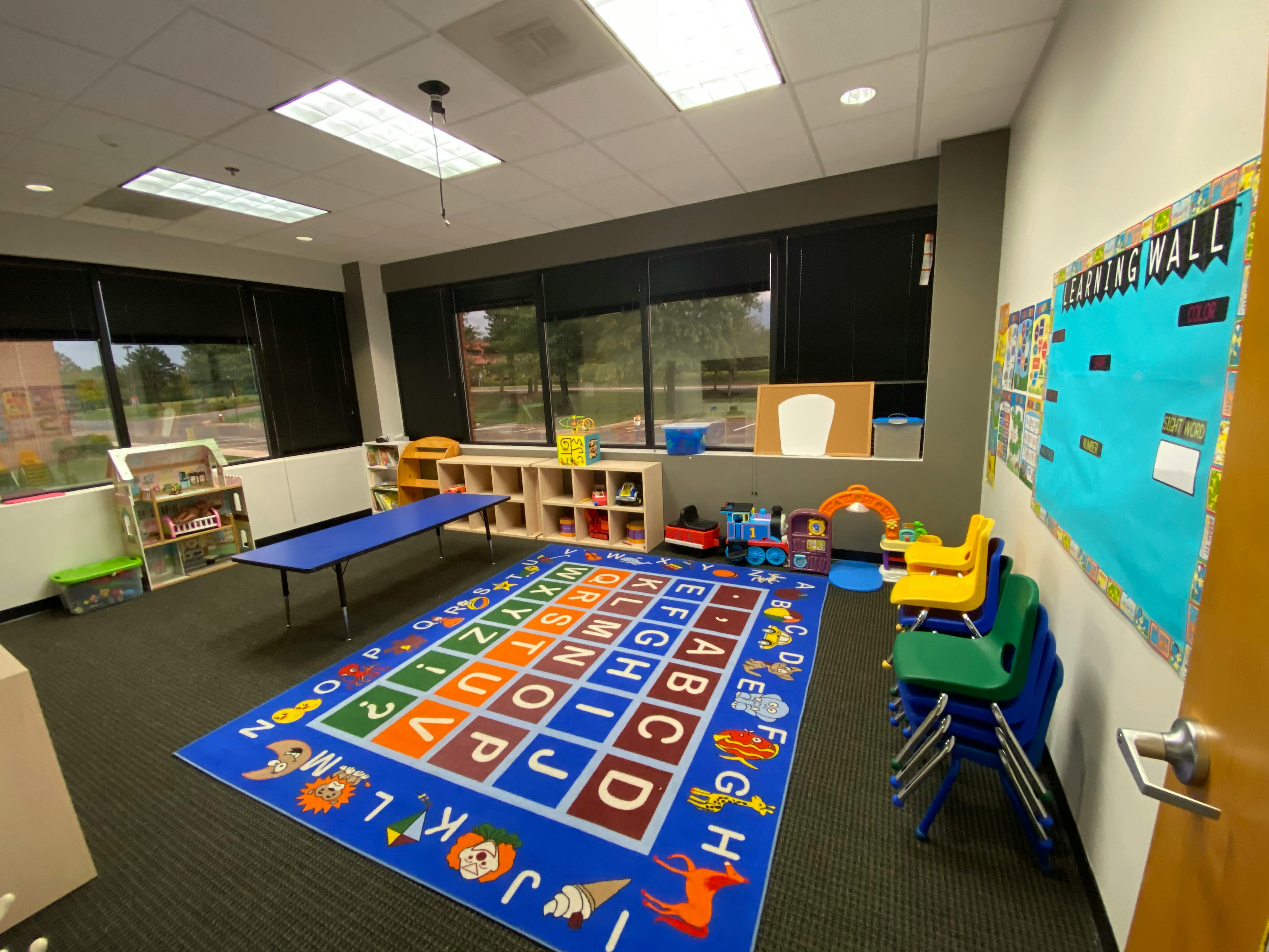 Empty classroom with an alphabet rug, small table, and chairs