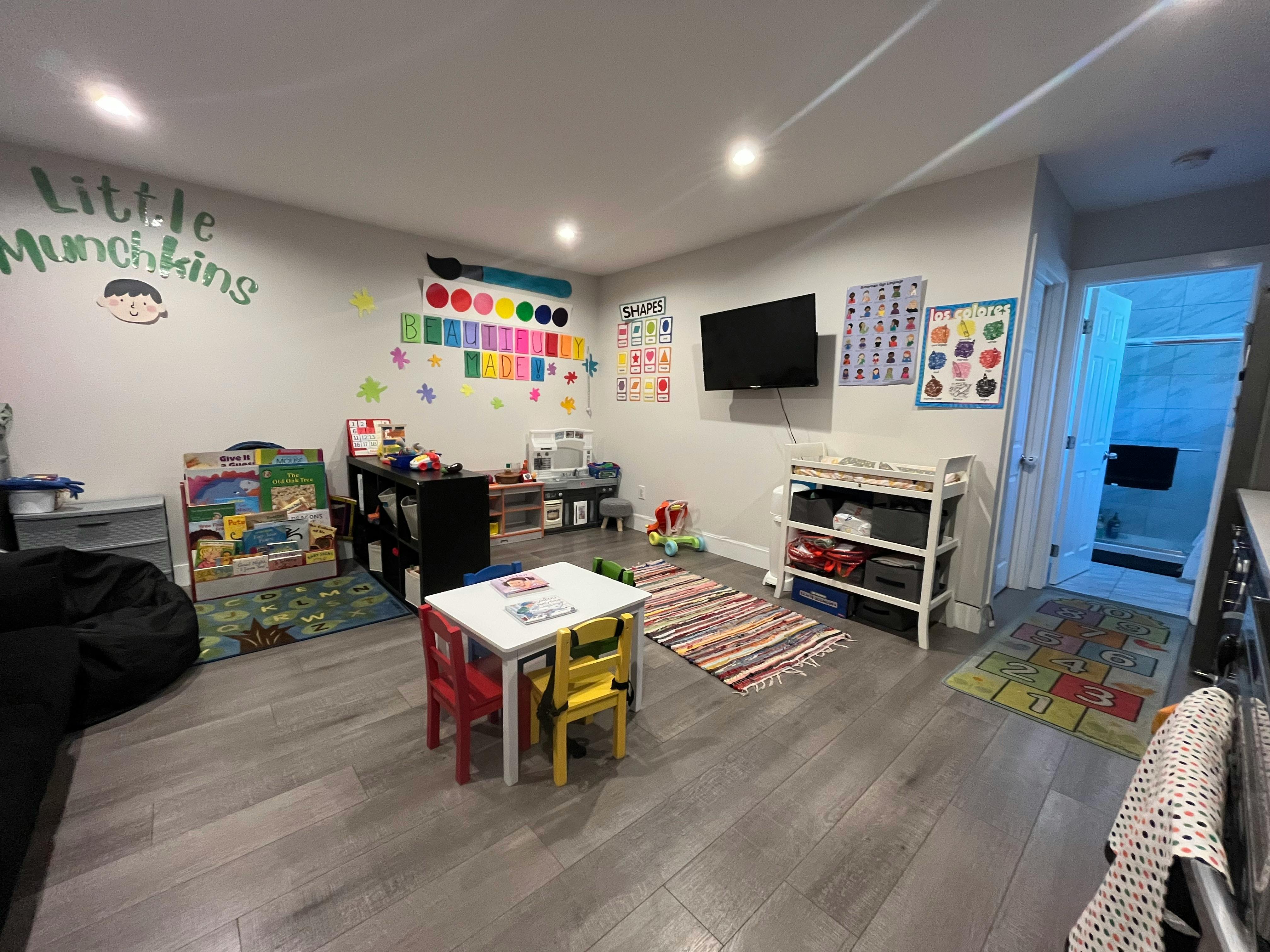 Playroom with small table and chairs, toys, and wall decorations