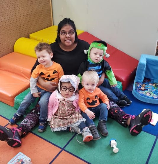 Person sitting with four children dressed in Halloween costumes