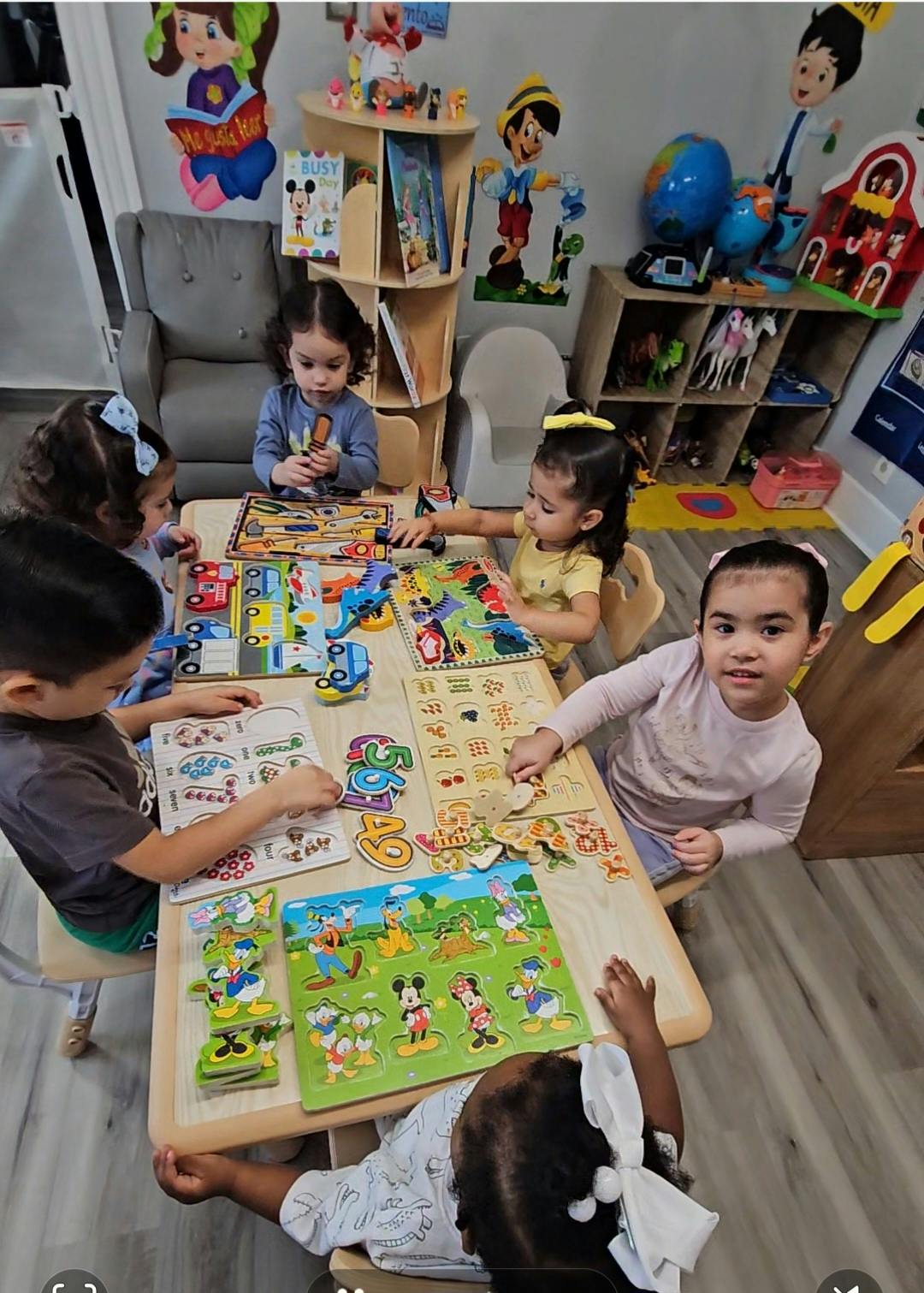 Five children sitting around a table playing with puzzles