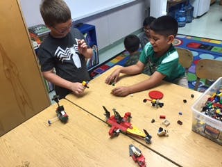 Two children playing with building blocks at a table