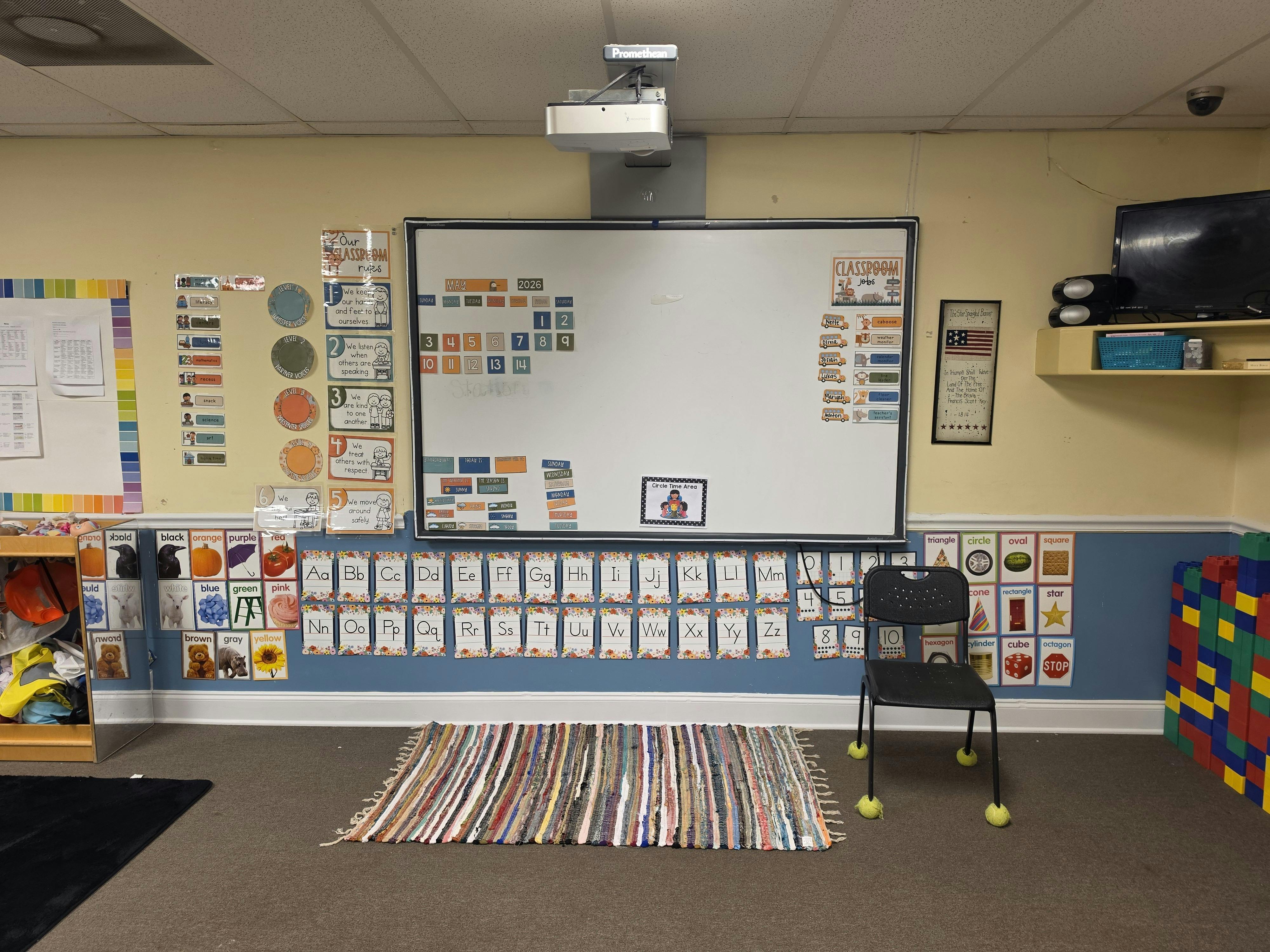 Classroom with whiteboard, projector, and educational posters on the walls