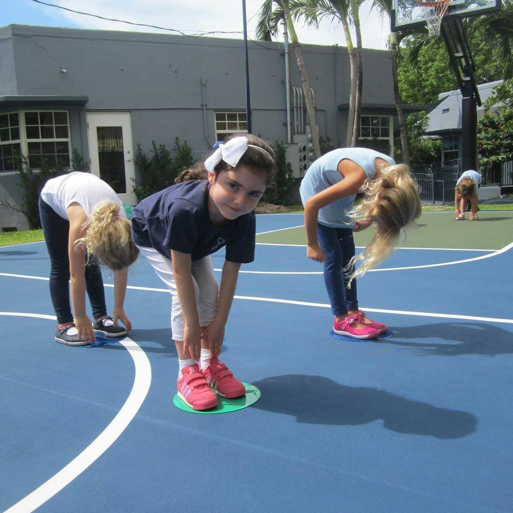 Children bending over on a blue court