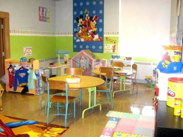 A classroom with small tables and chairs, toys, and a Mickey Mouse poster