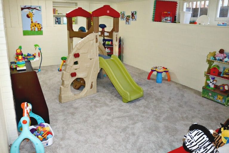 Indoor play area with a climbing structure, slide, and various toys